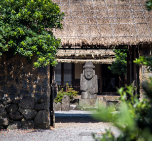 Traditionelles Haus mit Steinstatue auf Jeju in Südkorea.