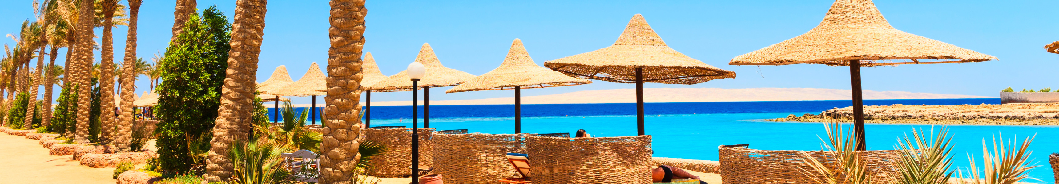 Sonniger Strand in El Gouna mit Palmen, Strohschirmen und Blick auf das Rote Meer in &Auml;gypten