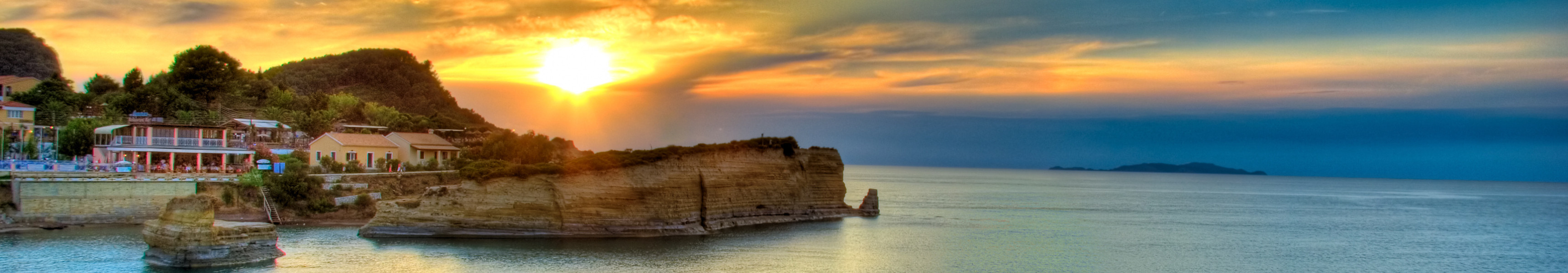 Sonnenuntergang an der K&uuml;ste von Korfu in Griechenland mit Felsen und Meerblick