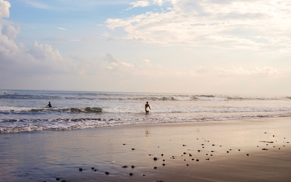 Surfer mit Surfbrett unter dem Arm am Traumstrand Noosa Beach
