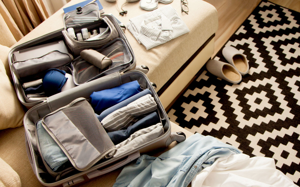 Gepackter Koffer mit unterschiedlichen Beuteln und gerollter Kleidung f&uuml;r mehr Platz und knitterfreie Kleidung.