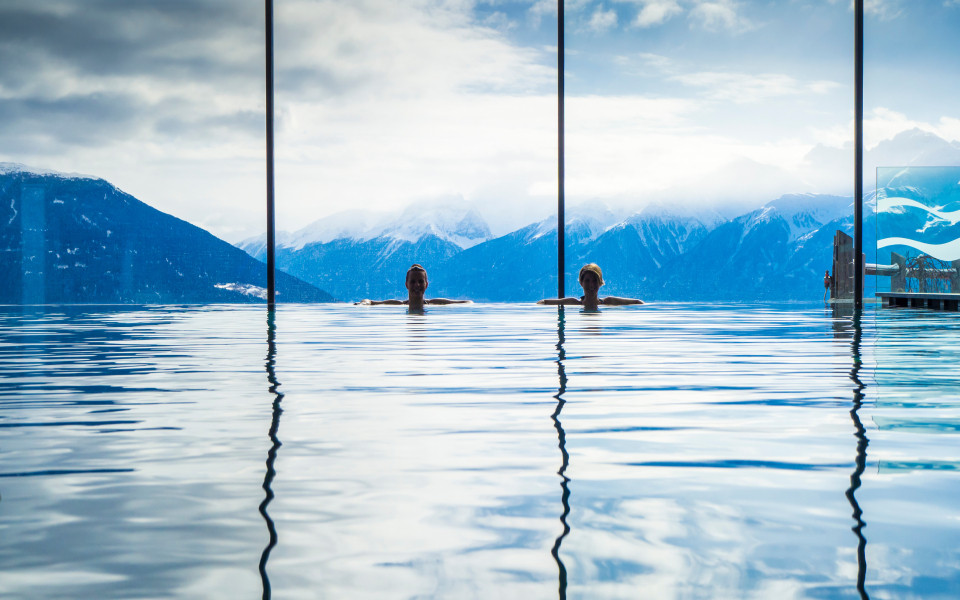 Frauen genie&szlig;en den Panoramablick vom Pool in die Alpen